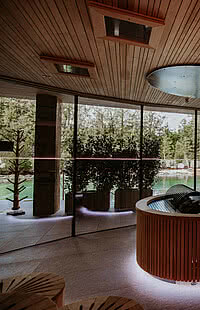 Innenausstattung mit vielen Holzelementen und großen Glasfronten der Teichsauna im Hang SPA im Genussdorf Gmachl in Bergheim bei Salzburg