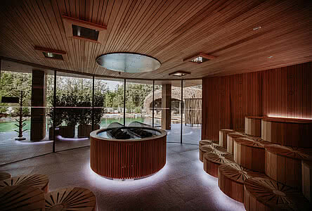 Innenausstattung mit vielen Holzelementen und großen Glasfronten der Teichsauna im Hang SPA im Genussdorf Gmachl in Bergheim bei Salzburg