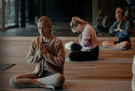 Frauen meditieren in einem stilvollen Yoga-Raum im Genussdorf Gmachl in Bergheim – perfekte Auszeit für einen Yoga Urlaub in Salzburg.