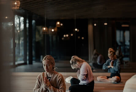 Frauen meditieren in einem stilvollen Yoga-Raum im Genussdorf Gmachl in Bergheim – perfekte Auszeit für einen Yoga Urlaub in Salzburg.