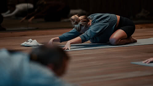 [Translate to English:] Eine Frau in einer Yogaposition auf einer Yogamatte