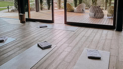 [Translate to English:] Ein heller Yogaraum mit Yogamatten auf dem Holzboden